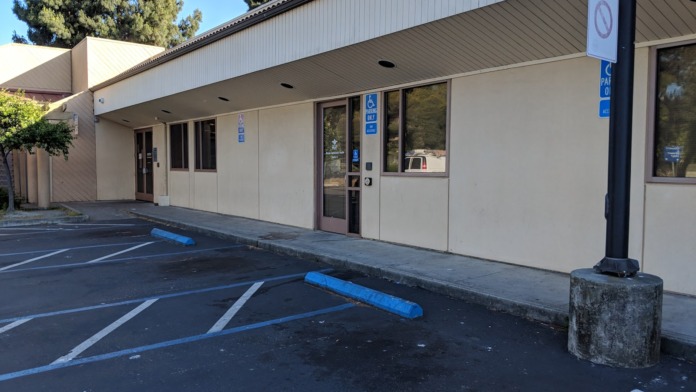 Exterior of treatment facility showing main entrance, accessible parking spaces with blue markings, and facility facade.