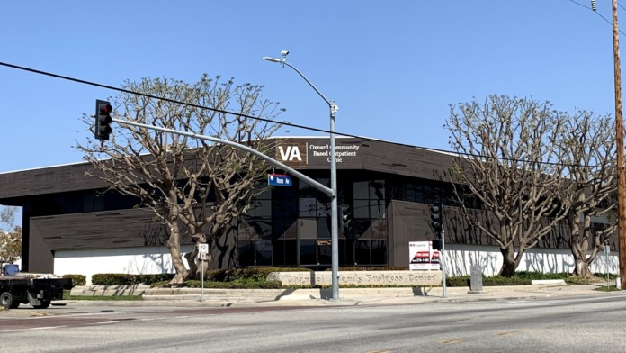 Exterior view of VA Oxnard Community Based Outpatient Clinic building entrance with black facade, signage, and landscaping