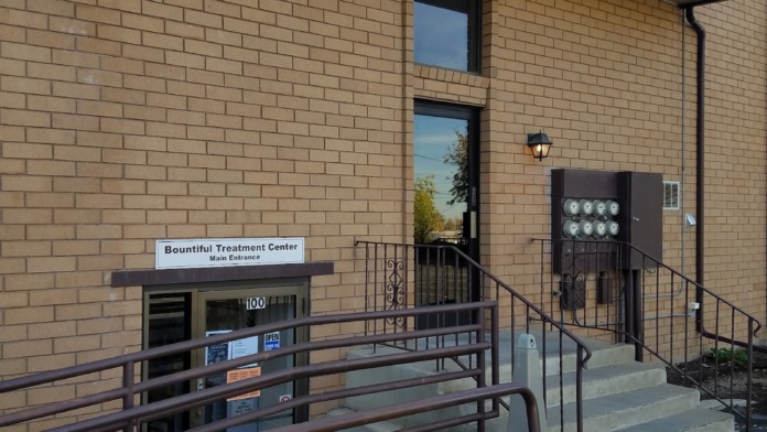 Exterior of brick treatment facility showing main entrance with metal railing, ADA accessible ramp, and signage