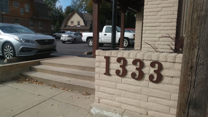 Exterior entrance detail showing building address numbers 1333 on brick facade with covered entry area and parked vehicles
