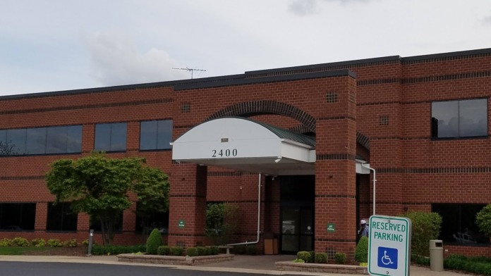 Exterior view of brick building entrance showing address 2400 with white awning and landscaping