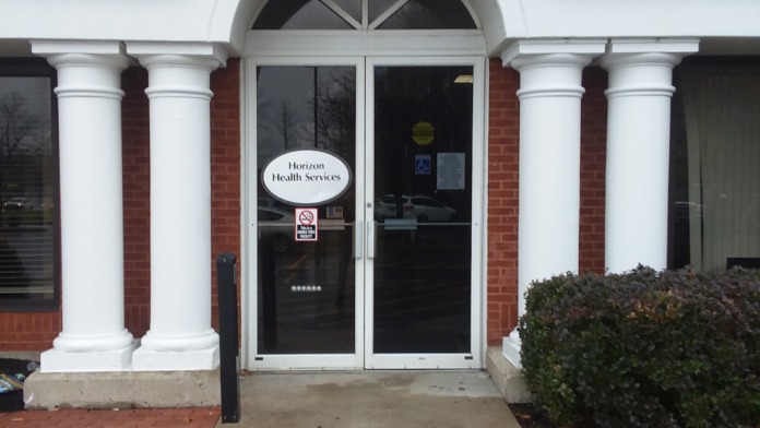 Exterior view of main entrance featuring brick facade, white columns, arched doorway, and Horizon Health Services signage
