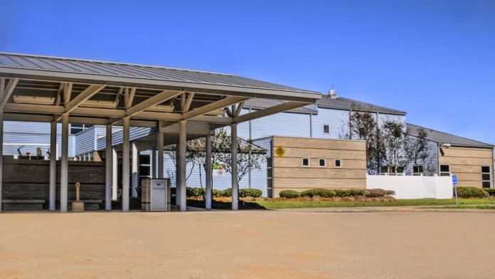 Exterior front entrance showing covered canopy structure, parking area, and modern facility facade with clear signage
