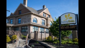Exterior front view of stone and brick treatment facility with main entrance, stairs, railing, and FamilyLinks sign