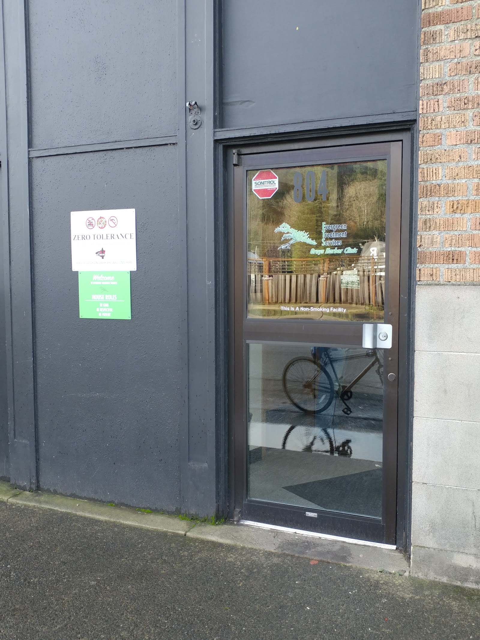 Exterior entrance door showing address 804 with welcome signage, zero tolerance policy notice, and non-smoking facility indicator