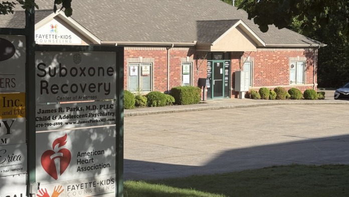Exterior view of Suboxone Recovery Center of Arkansas brick building with main entrance, landscaping, and directional signage visible