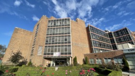 Exterior view of brick treatment facility building with main entrance, flowering plants, and clear signage