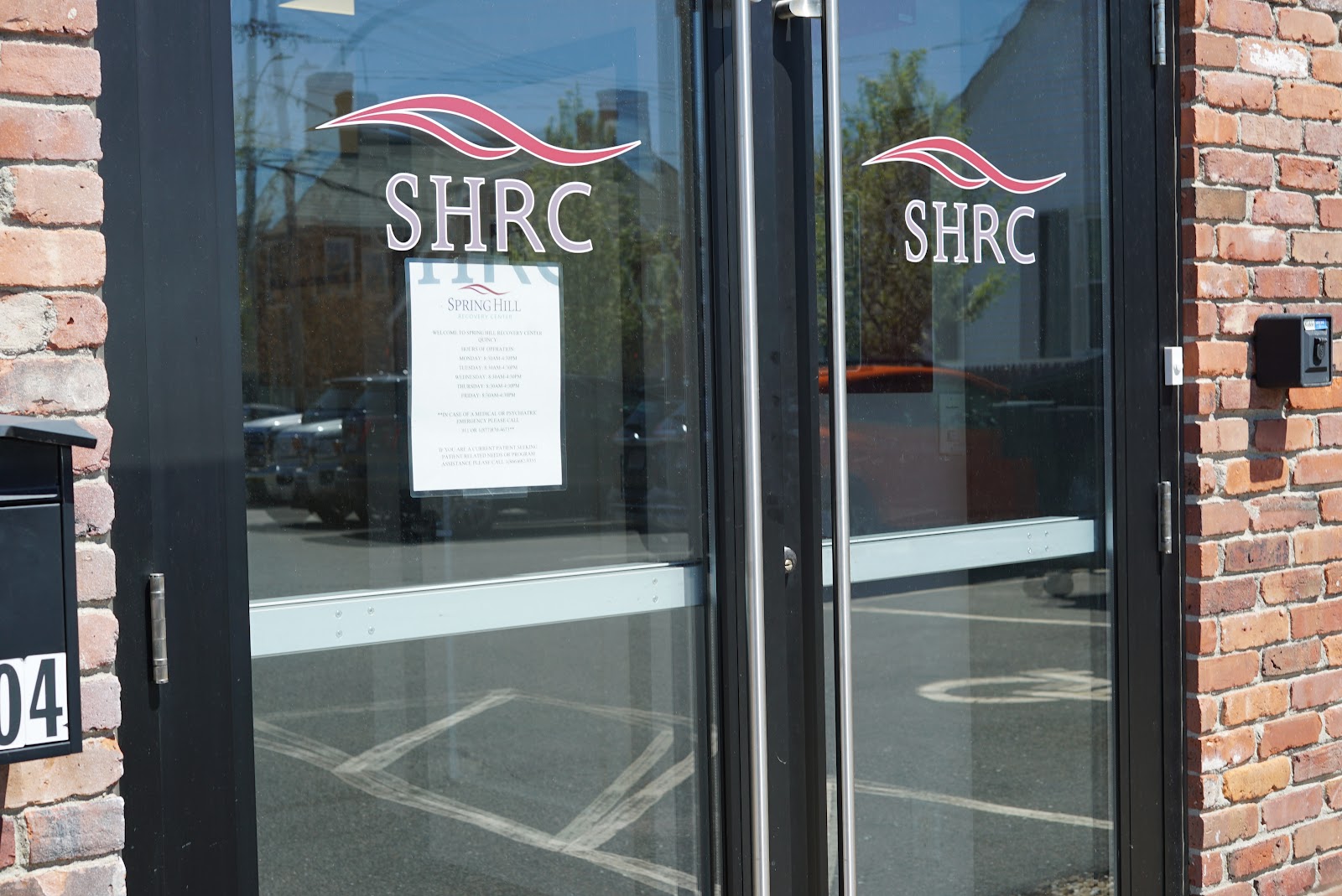 Exterior view of facility entrance showing SHRC logo on glass doors with brick facade and address marker