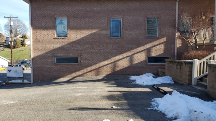 Exterior front view of brick treatment facility with main entrance, Valley HealthCare sign visible, and parking area