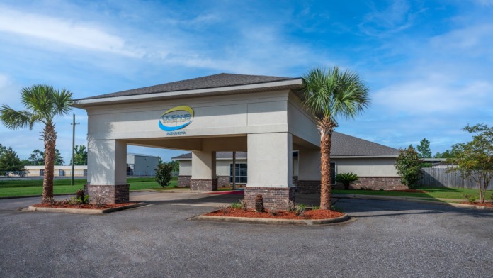 Exterior canopy entrance with Oceans Behavioral Hospital branding, palm tree landscaping, and brick architectural features