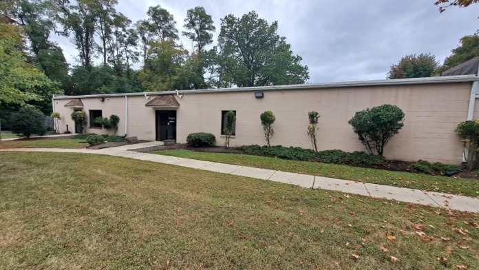 Exterior view of single-story treatment facility with cream-colored brick facade, landscaped grounds, and manicured lawn area