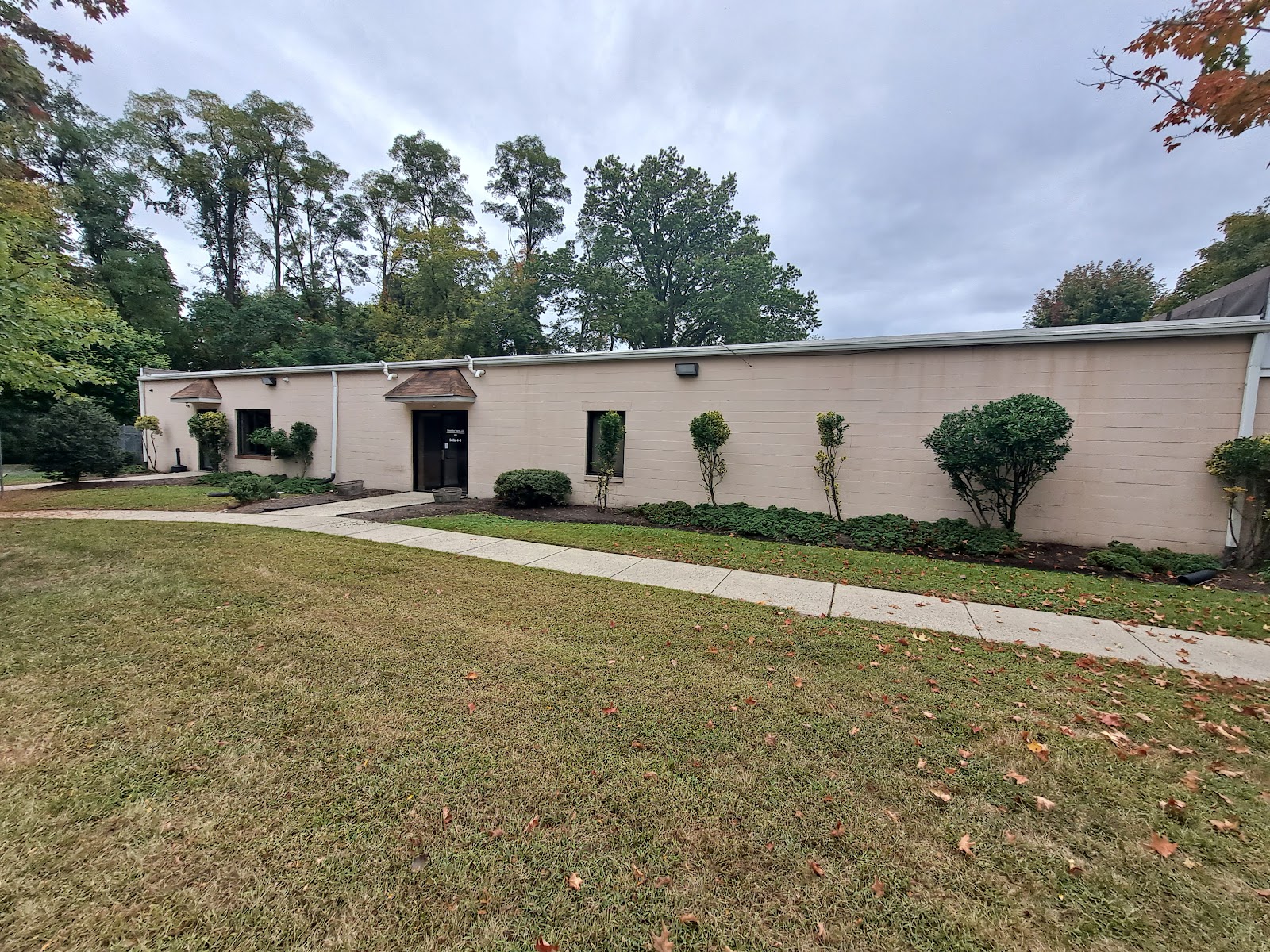 Exterior view of single-story treatment facility with cream-colored brick facade, landscaped grounds, and manicured lawn area