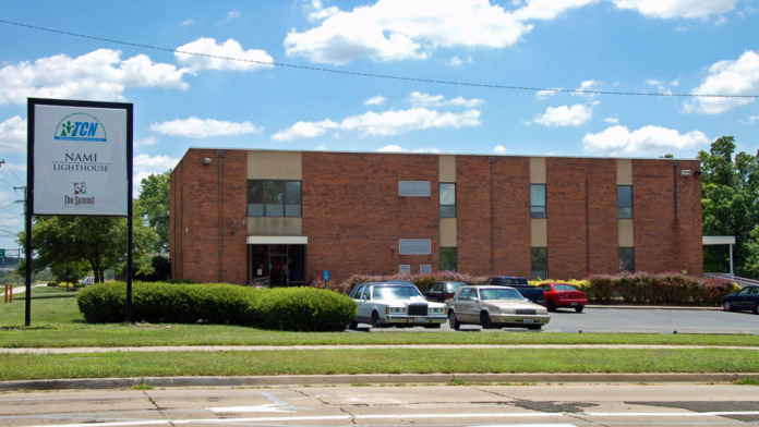 Exterior view of brick treatment center building with parking area, landscaping, and facility signage visible