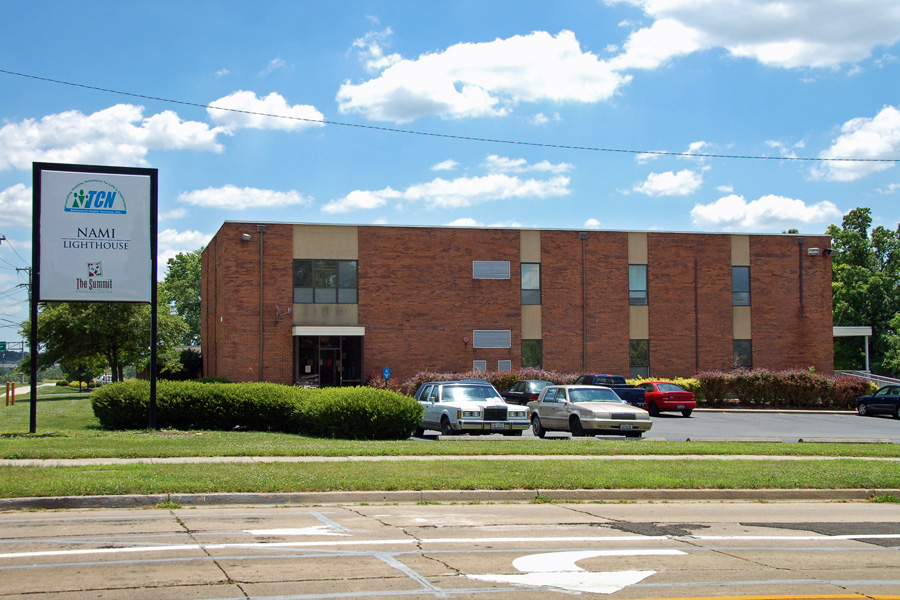 Exterior view of brick treatment center building with parking area, landscaping, and facility signage visible