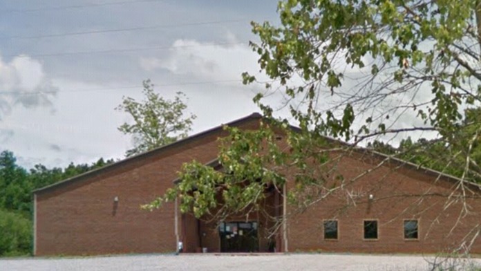 Exterior view of brick treatment center building with parking area, landscaping, and natural surroundings