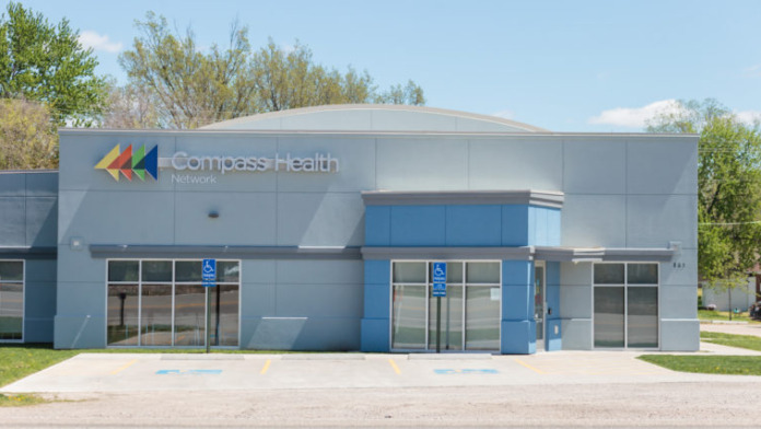 Exterior of modern Compass Health Network Butler building with blue entrance doors, accessible parking, and facility signage.