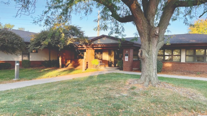 Exterior view of brick treatment center building with large tree, landscaped grounds, and main entrance