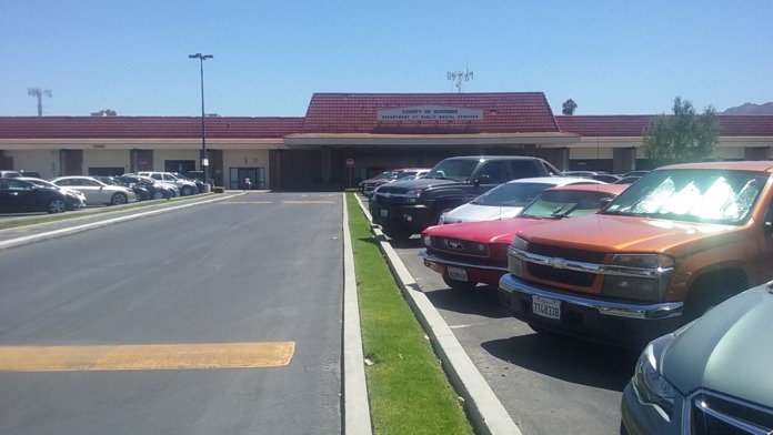 Exterior full view of County of Riverside mental health facility with red tile roof and landscaped parking area
