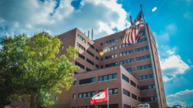 Exterior view of multi-story brick hospital building with American flag and institutional flags displayed