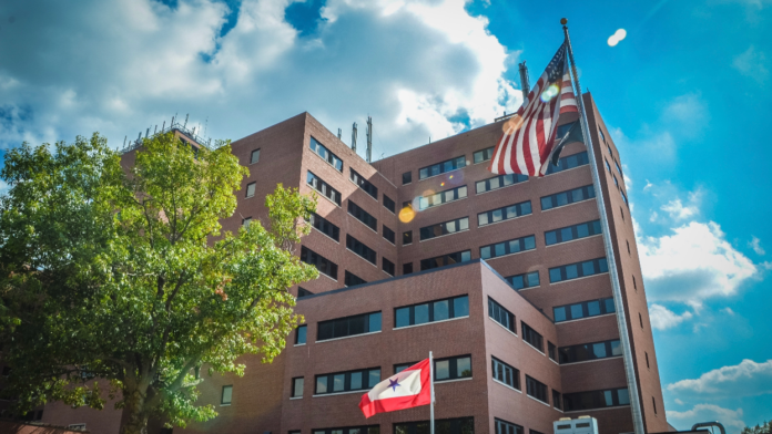 Exterior view of multi-story brick hospital building with American flag and institutional flags displayed