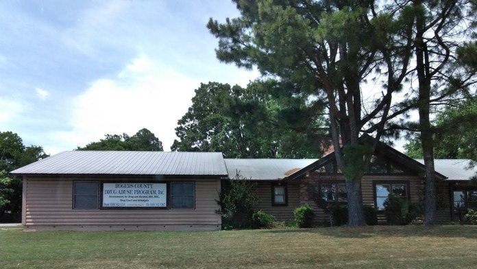 Exterior view of Rogers County Drug Abuse Program facility showing log cabin-style building with metal roof and entrance signage