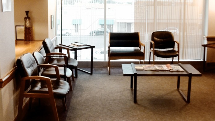 Interior main lobby with curved wooden reception counter, elevator, seating areas, and natural lighting