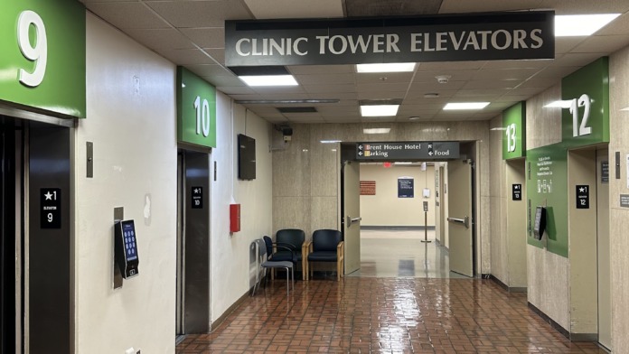 Interior hallway showing multiple elevators, directional signage, seating area, and polished flooring