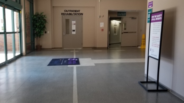 Interior lobby space with modern flooring, outpatient rehabilitation signage, and wayfinding displays