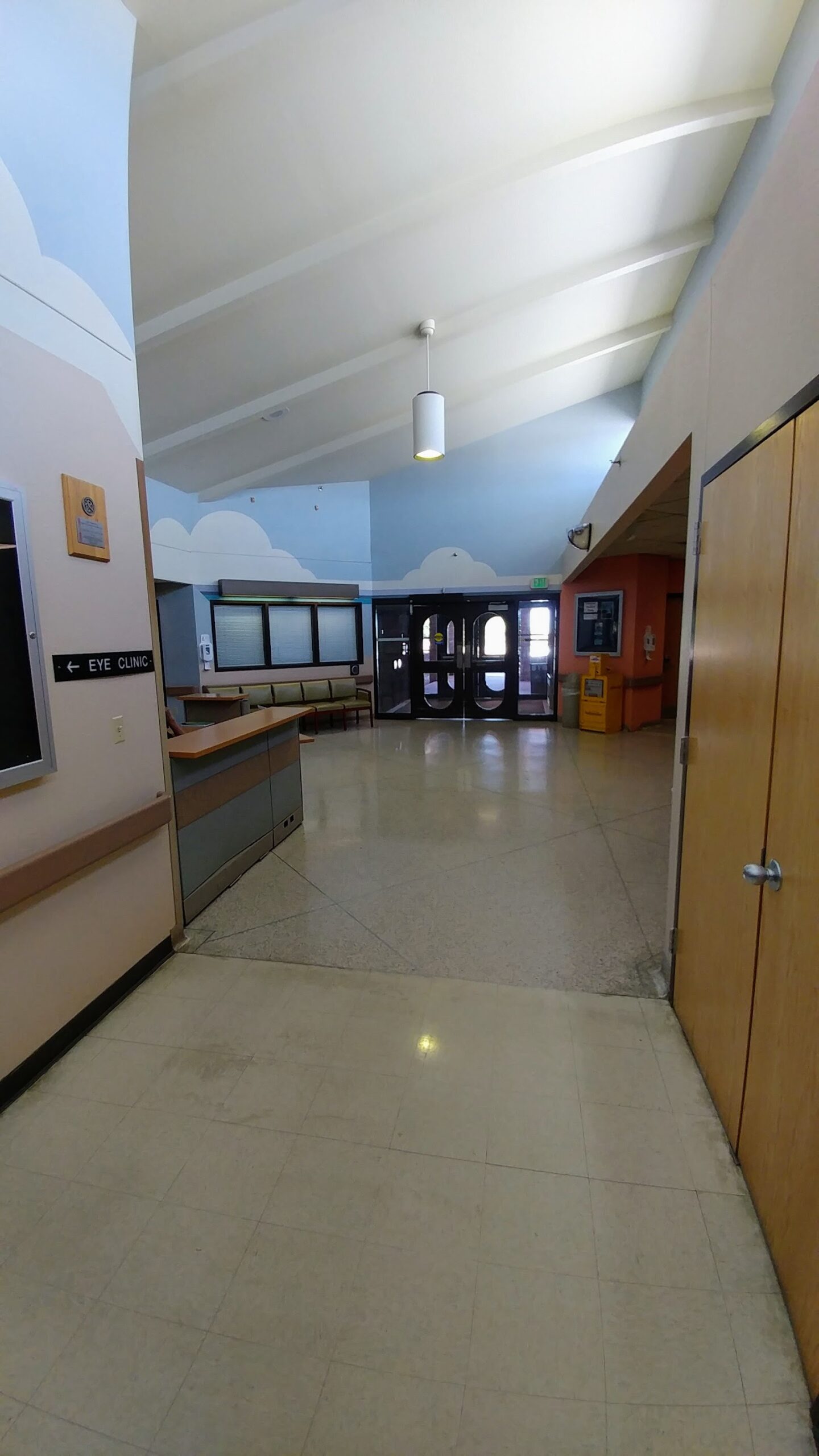 Interior lobby space with high ceilings, treatment check-in desk, waiting seating, and cloud-themed wall murals