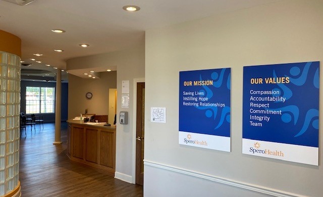 Interior lobby space with reception desk, hardwood flooring, and visible mission and values signage on walls