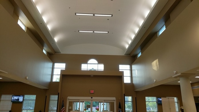 Interior main lobby with vaulted ceiling, skylights, large glass doors, and American flags