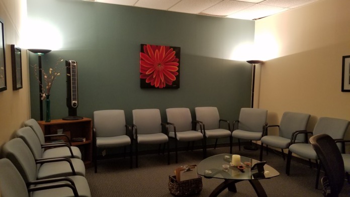 Interior lounge space with multiple upholstered chairs arranged around a glass table, decorative artwork on walls