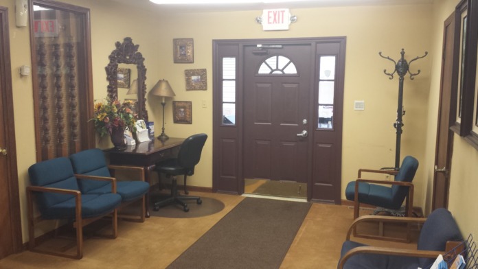 Interior reception area with comfortable seating, main entrance door, and professional furnishings