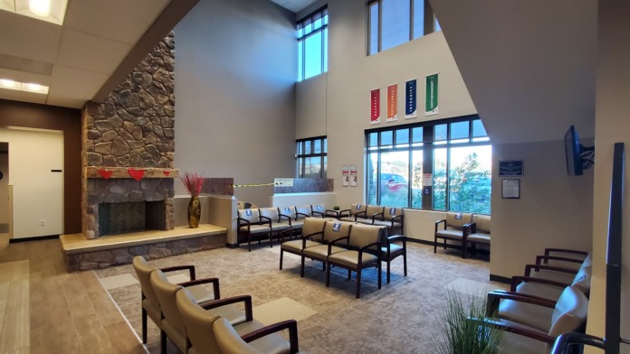 Interior waiting area with stone fireplace feature, comfortable seating, and tall windows