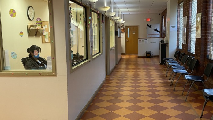 Interior corridor with display windows, reception desk, seating area, and diamond patterned floor