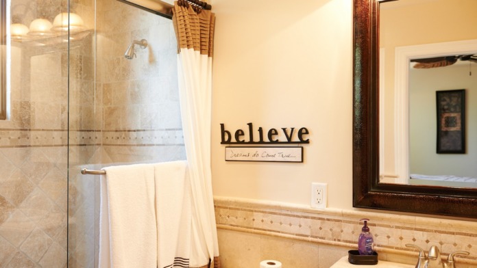 Interior spa bathroom with walk-in shower, soaking tub, decorative wall text reading 'believe', dual sinks, and marble finishes