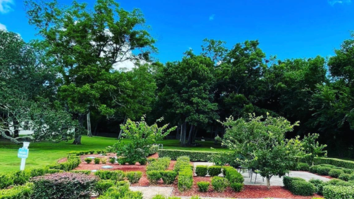 Exterior meditation garden featuring walkways, shrub landscaping, native plants, mature trees, and open lawn areas