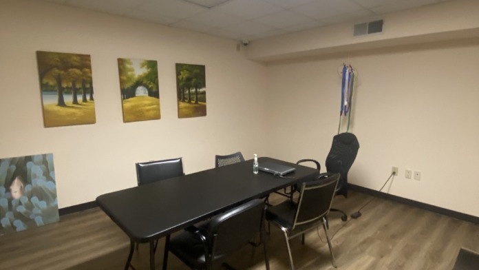 Interior meeting space with black table, chairs, landscape artwork, and LED skylight ceiling panel