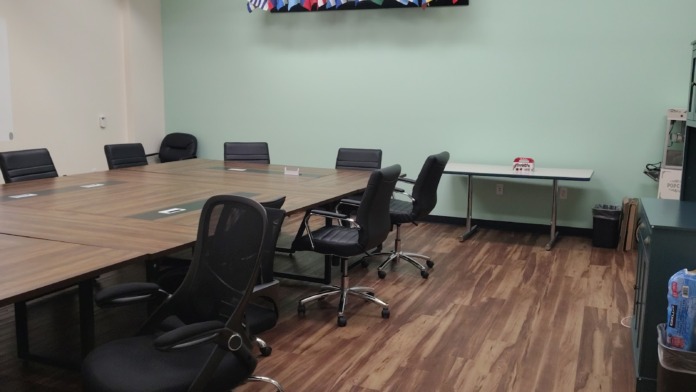 Interior meeting room with large conference table, ergonomic chairs, international flags displayed on wall, and polished flooring