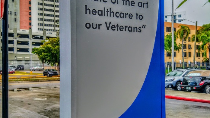 Exterior signage displaying facility mission statement with landscaping and facility buildings
