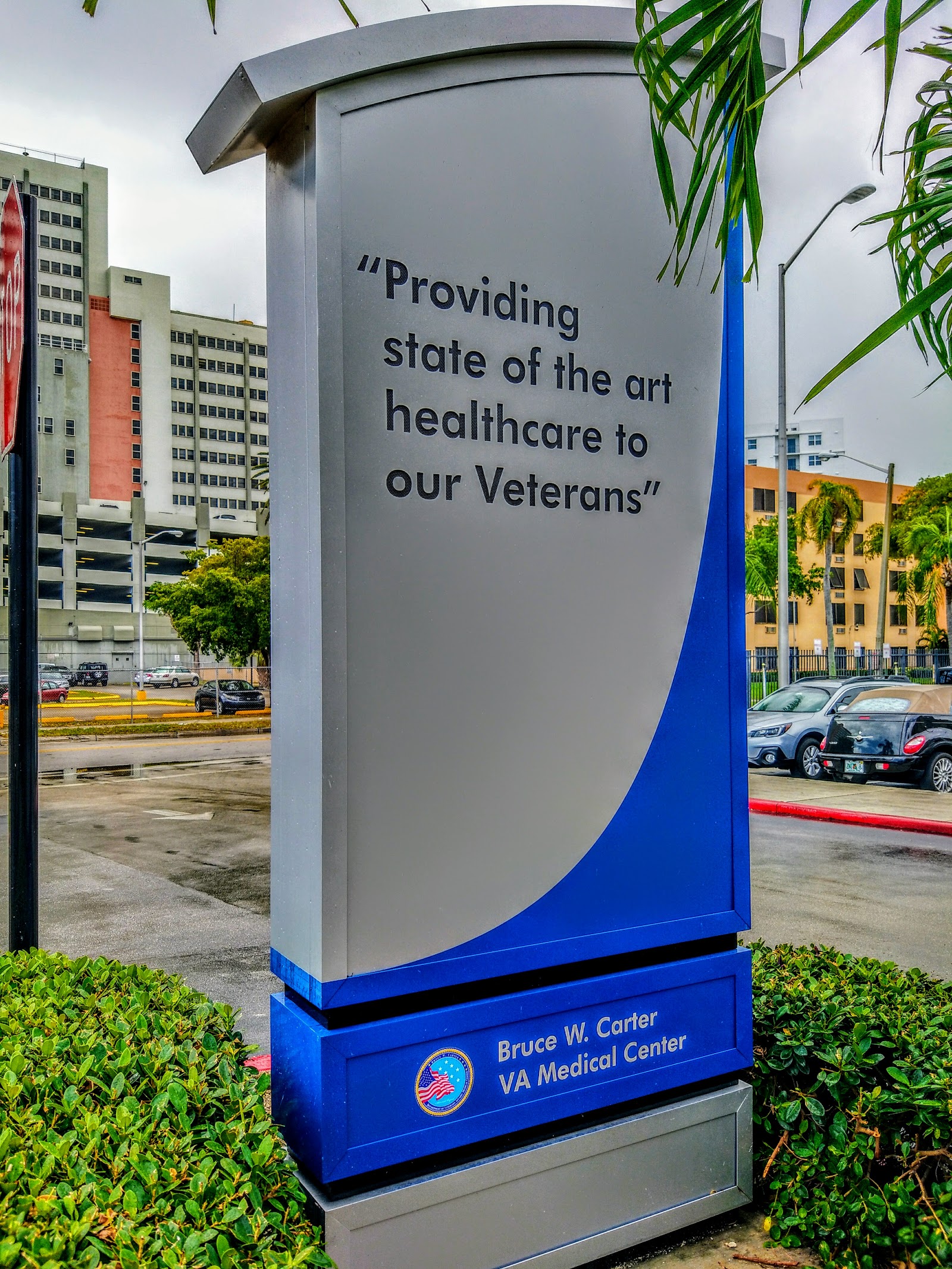 Exterior signage displaying facility mission statement with landscaping and facility buildings