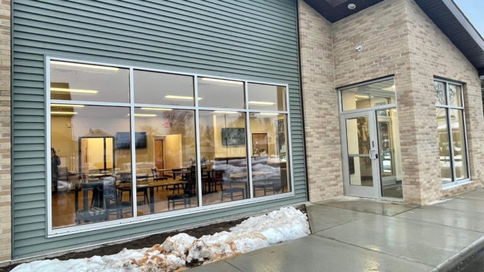 Exterior showing modern glass windows of illuminated interior space with furniture and concrete patio.
