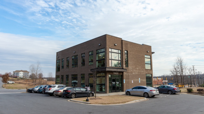 Exterior view of modern brick treatment facility building with glass entrance, parking lot, and landscaping