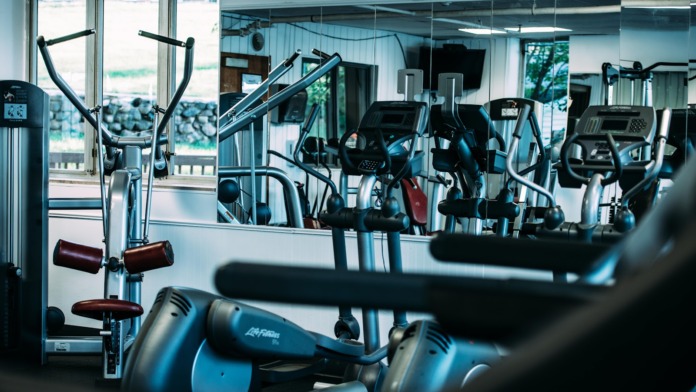 Interior fitness facility with multiple exercise machines, mirrored walls, and natural lighting throughout