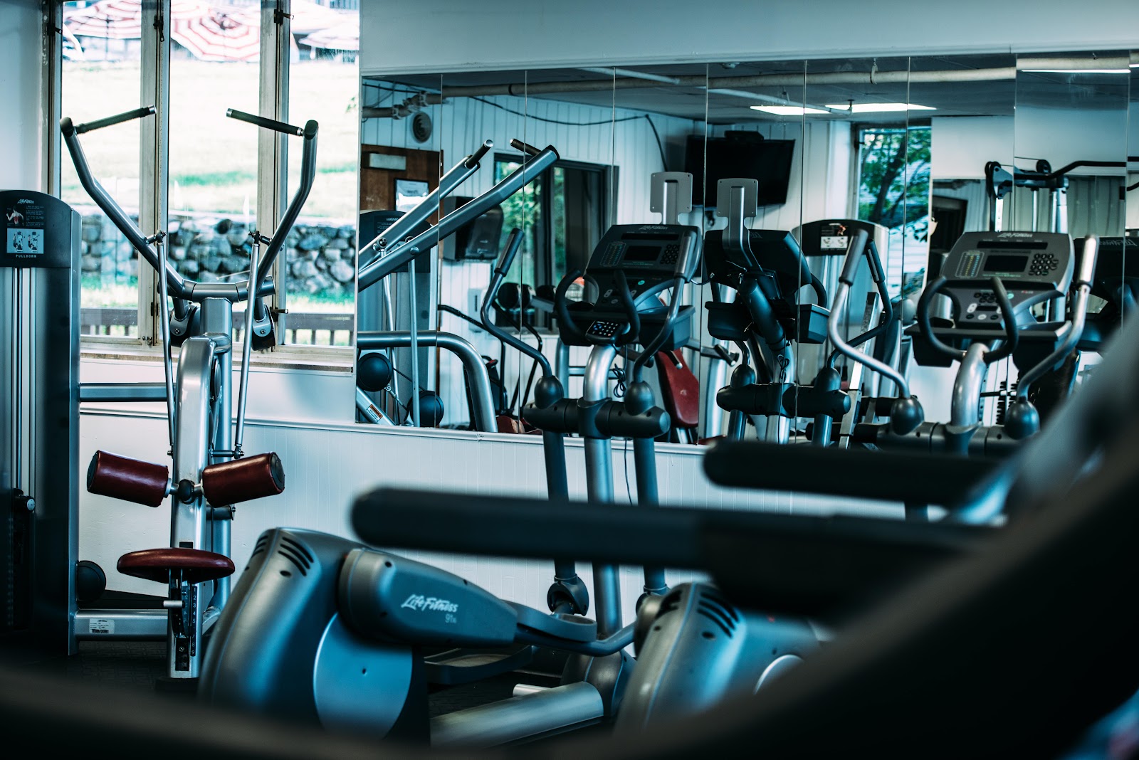 Interior fitness facility with multiple exercise machines, mirrored walls, and natural lighting throughout