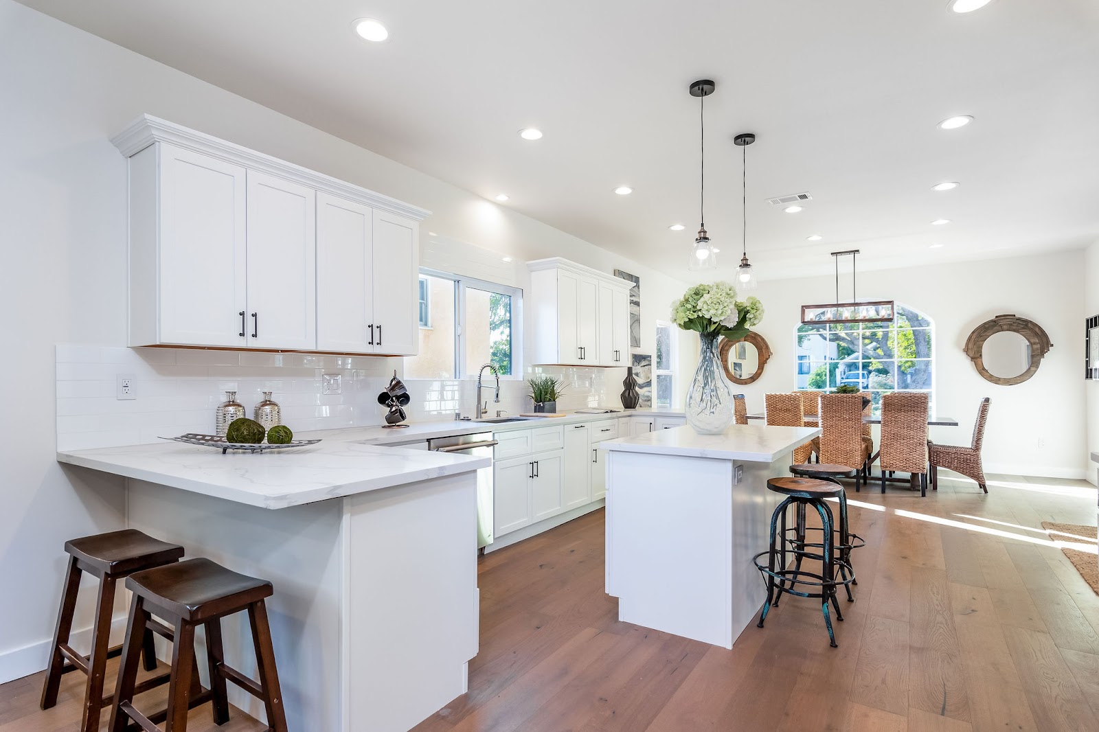Interior kitchen with white cabinetry, large island, pendant lighting, and open floor plan to dining area