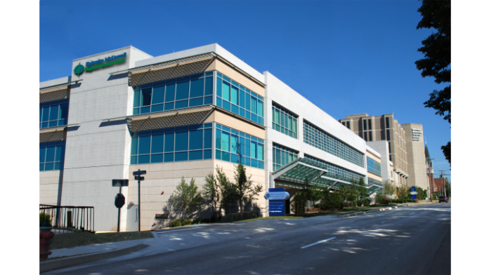 Exterior of modern multi-story medical facility with white and turquoise facade, glass windows, and covered entrance