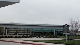 Exterior of single-story medical building with glass windows, brick base, landscaped grounds with agave plants and covered entrance