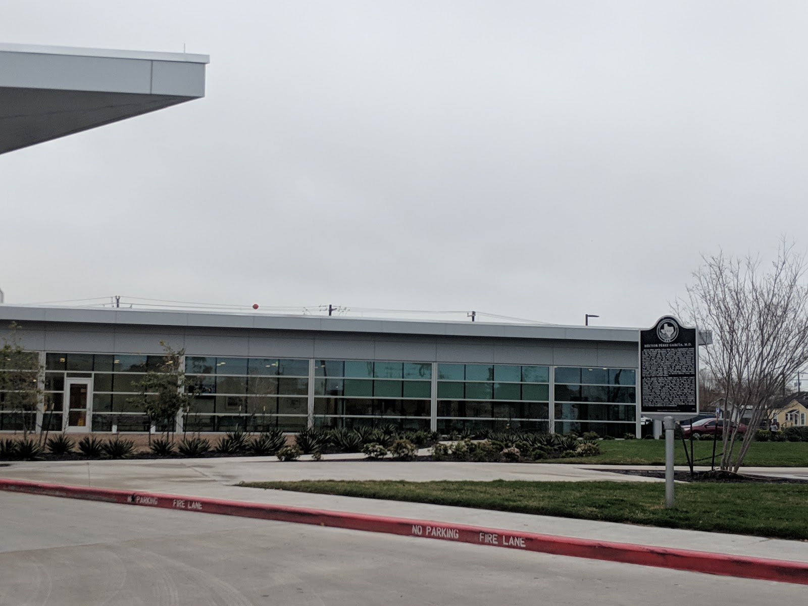 Exterior of single-story medical building with glass windows, brick base, landscaped grounds with agave plants and covered entrance