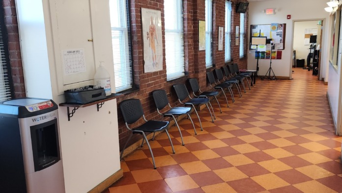 Interior common area with exposed brick walls, window seating, bulletin board with notices, and water dispenser